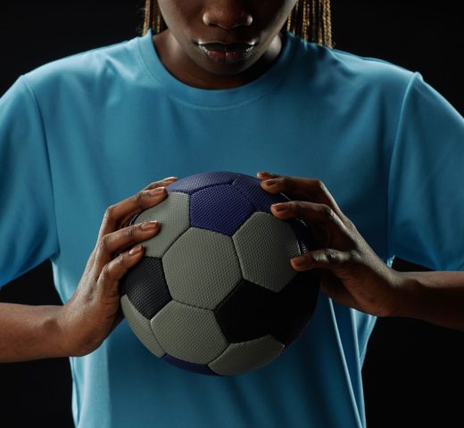 Cropped concept shot of female football player holding ball to chest and looking down copy space